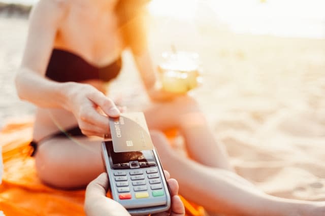 Woman on the beach making contactless credit card payment   ++++ Note for the inspector: Credit card is fake ++++