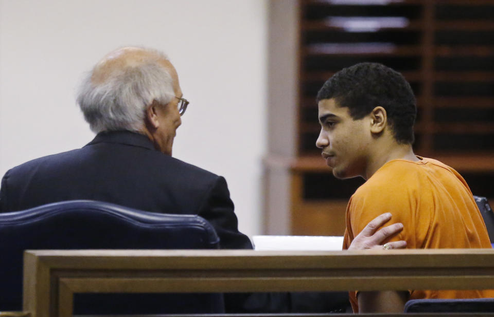 In this photo shot through a courtroom door, defendant Chancey Luna, right, talks with one of his attorneys, Jim Berry, left, following a hearing in Duncan, Okla, Wednesday, March 12, 2014. Luna is charged in the murder of Australian Christopher Lane. (AP Photo/Sue Ogrocki)