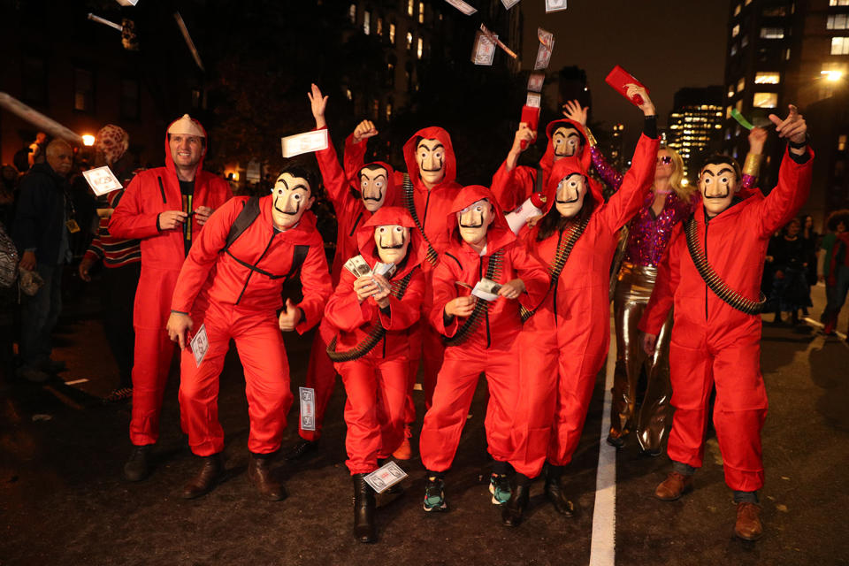 People wearing Salvador Dail masks fire paper money in the air during the Halloween Parade in Lower Manhattan of New York City. (Photo: Gordon Donovan/Yahoo News)