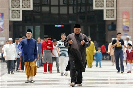 A Muslim man prays as he and others leave a mosque following Friday prayers in Kuala Lumpur March 21, 2014. REUTERS/Damir Sagolj