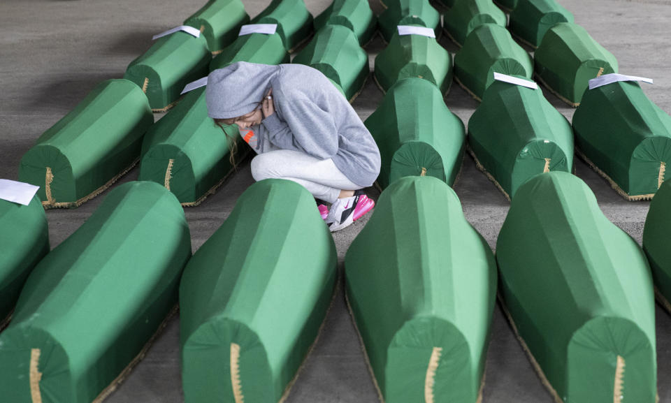A girl inspects coffins prepared for burial, in Potocari near Srebrenica, Bosnia, Wednesday, July 10, 2019. The remains of 33 victims of Srebrenica massacre will be buried on July 11, 2019, 24 years after Serb troops overran the eastern Bosnian Muslim enclave of Srebrenica and executed some 8,000 Muslim men and boys, which international courts have labeled as an act of genocide. (AP Photo/Darko Bandic)