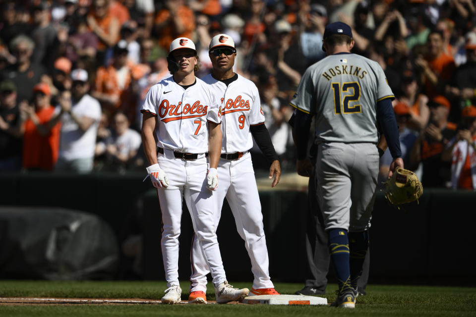 Baltimore Orioles' Jackson Holliday (7) stands at first next to first base coach Anthony Sanders (9) after hitting a single during the seventh inning of a baseball game against the Milwaukee Brewers, Sunday, April 14, 2024, in Baltimore. Brewers first baseman Rhys Hoskins (12) looks on. (AP Photo/Nick Wass)