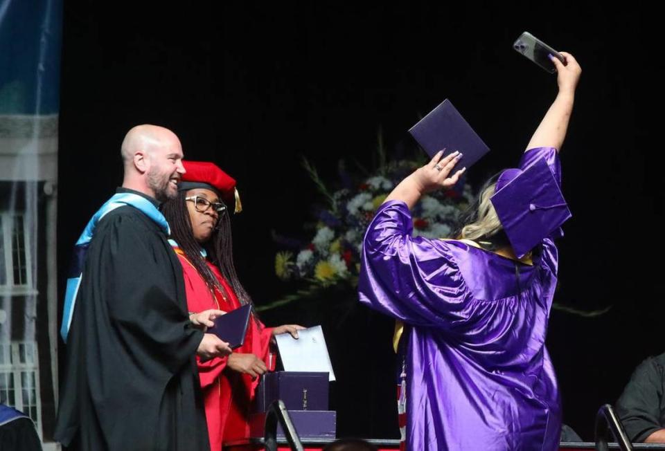 A graduate snaps a selfie on stage during the Fresno High graduation ceremony held at the Save Mart Center on June 5, 2023.