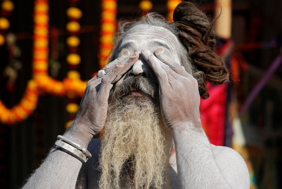 A Sadhu applies ash on his face at a makeshift shelter