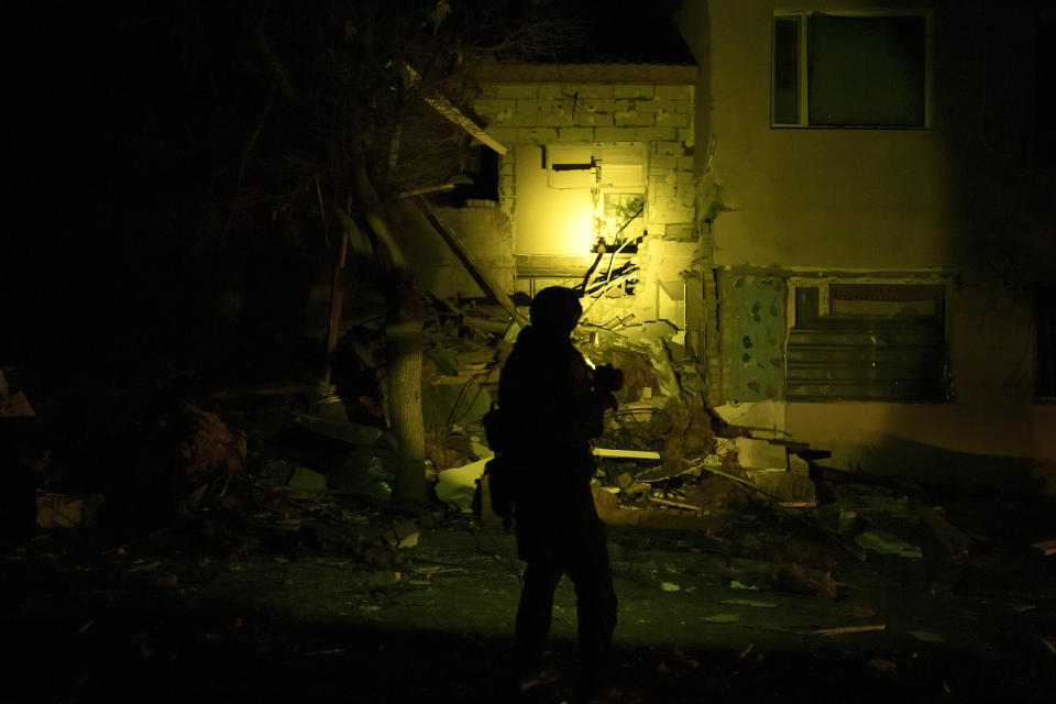 A Ukrainian special police officer walks next to a destroyed building as he patrols during a night curfew in Kharkiv, Ukraine, Sunday, March 27, 2022. (AP Photo/Felipe Dana)