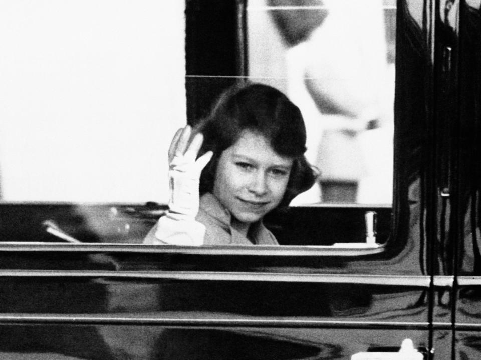 Young Elizabeth waving from a car.