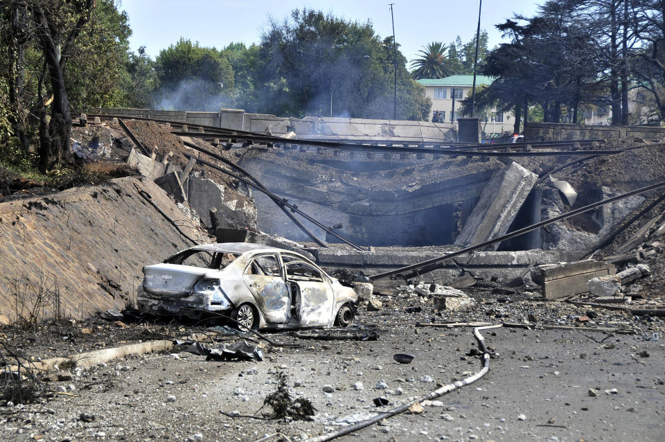 A burned out vehicle marks the spot where a gas tanker exploded under a bridge in Boksburg, east of Johannesburg, Saturday, Dec. 24, 2022. A truck carrying liquified petroleum gas has exploded in the South African town of Boksburg, killing at least 8 people and injuring more than 50 others on Saturday. (AP Photo/Hein Kaiser)