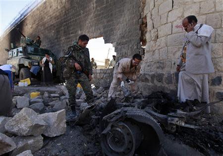 Investigators from the criminal investigation department (CID) examine the wreckage of a car after a bomb exploded outside the main wall of the central prison in Sanaa February 14, 2014. REUTERS/Mohamed al-Sayaghi