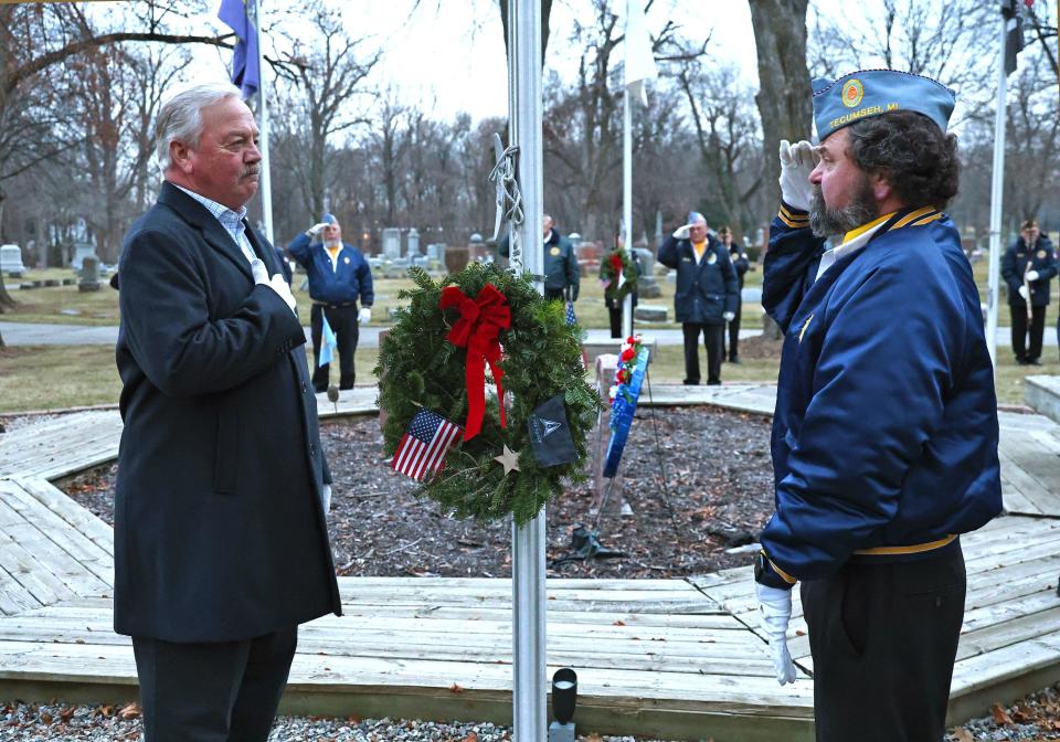 Tecumseh Mayor Jack Baker, left, places his hand over his heart and receives a salute from Dan Dotsen, right, after hanging a ceremonial wreath in honor of the United States Space Force Division Saturday, Dec. 16, 2023, during a Wreaths Across America ceremony in Tecumseh at Brookside Cemetery.