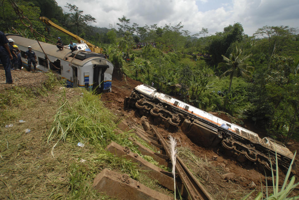 Worker remove derailed trains in Tasikmalaya, West Java, Indonesia, Saturday, April 5, 2014. A passenger train hit mounds of mud triggered by a landslide and derailed in central Indonesia, killing at least three people and injuring seven, a railway official said Saturday. (AP Photo/Erwin Gobel)