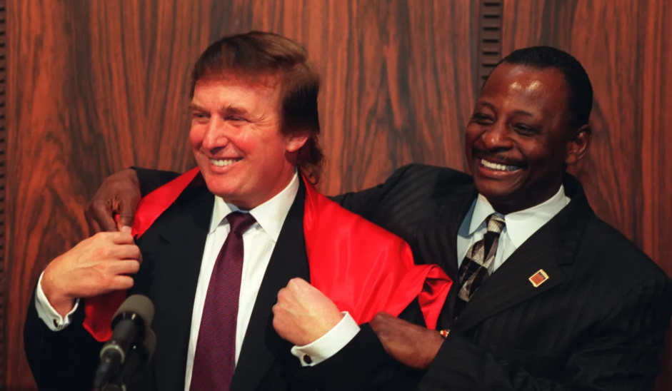 Donald Trump laughs as Mel Farr, right, drapes a cape over Trump's shoulders at a press conference at the Fisher Theater in 1997. The two were partners in a casino venture that never came to fruition. Farr wore the signature cape in TV commercials for his auto dealerships.