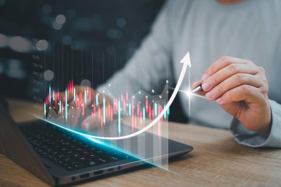 A hand sketching a holographic stock chart.