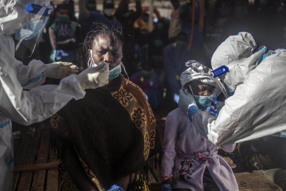 Santa, una mujer de 25 años de Costa de Marfil, y su hija Timi, de 5 años y con un gorro térmico en la cabeza, se someten a un test de antígenos para comprobar que no tienen coronavirus tras ser rescatadas en aguas internacionales del Mar Mediterráneo por el barco de la ONG Open Arms, el 16 de febrero de 2021. En los últimos días, las autoridades libias han impedido ocho intentos de rescate por parte del Open Arms, el barco de la ONG española del mismo nombre, acosando y amenazando a su tripulación. (AP Foto/Bruno Thevenin)