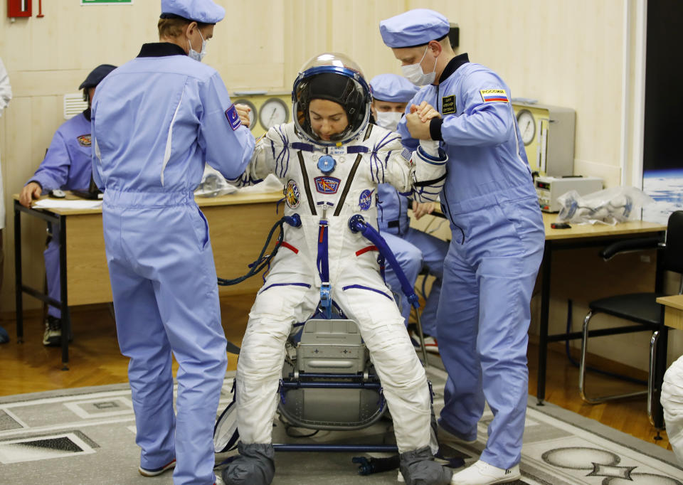 Russian Space Agency experts help U.S. astronaut Jessica Meir, member of the main crew of the expedition to the International Space Station (ISS), to stand up after inspecting her space suit prior the launch of Soyuz MS-15 space ship at the Russian leased Baikonur cosmodrome, Kazakhstan, Wednesday, Sept. 25, 2019. (AP Photo/Dmitri Lovetsky)