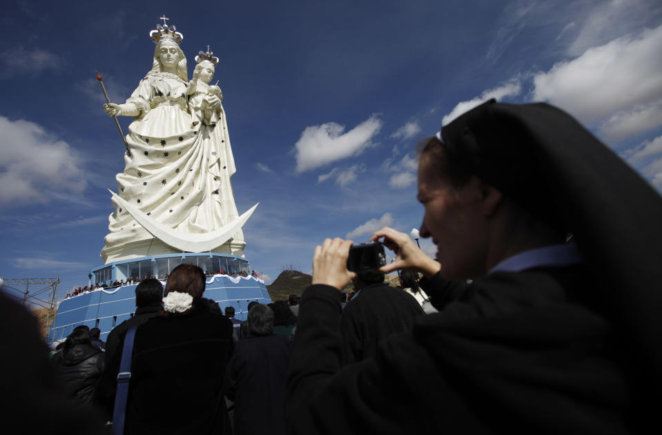A nun takes pictures of a newly unveiled statue of the Virgin Mary holding a baby Jesus on Santa Barbara hill in the mining city of Oruro, Bolivia, Friday, Feb. 1, 2013. The 45 meter (147 feet) statue that took four years to build, known in Spanish as "Virgen del Socavón," or the Virgin of the Tunnel, is Oruro's patron, venerated in particular by miners and folkloric Carnival dancers. (AP Photo/Juan Karita)