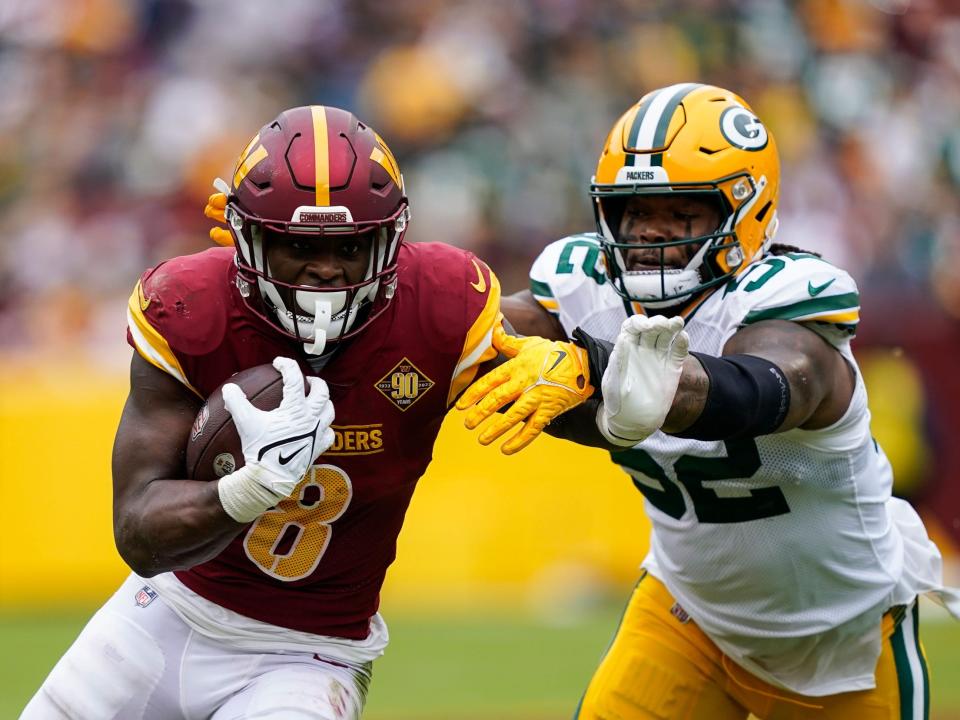 Brian Robinson fights off a defender against the Green Bay Packers.