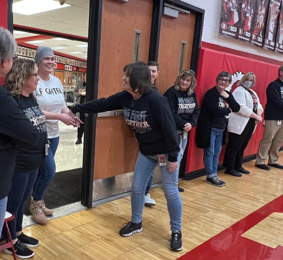 Justine Moodespaugh, center, welcomes Bucyrus High School secretary Fran Swavel to a pep rally in the school gymnasium on Tuesday that was planned by DECA students in honor of her battle against cancer.