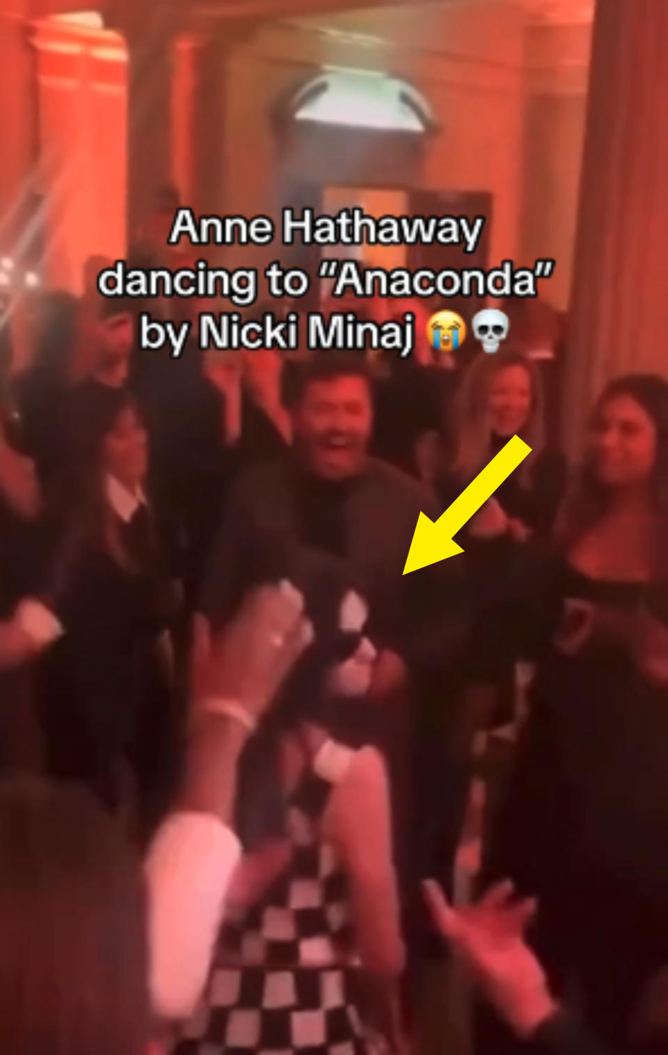 Anne Hathaway dancing to "Anaconda" by Nicki Minaj in a lively event surrounded by people