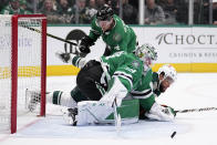 Dallas Stars goaltender Jake Oettinger (29) is hit by a sliding Minnesota Wild's Jordan Greenway, bottom rear, as Oettinger defends against a shot during the second period of an NHL hockey game Wednesday, Feb. 8, 2023, in Dallas. Stars defenseman Miro Heiskanen is at rear. (AP Photo/Tony Gutierrez)