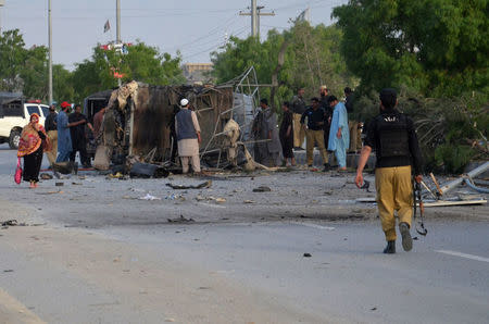 Policemen, plain clothes security members and locals gather near a destroyed police truck, after three suicide bomb attacks in southwestern city of Quetta, Pakistan April 24, 2018. REUTERS/Naseer Ahmed