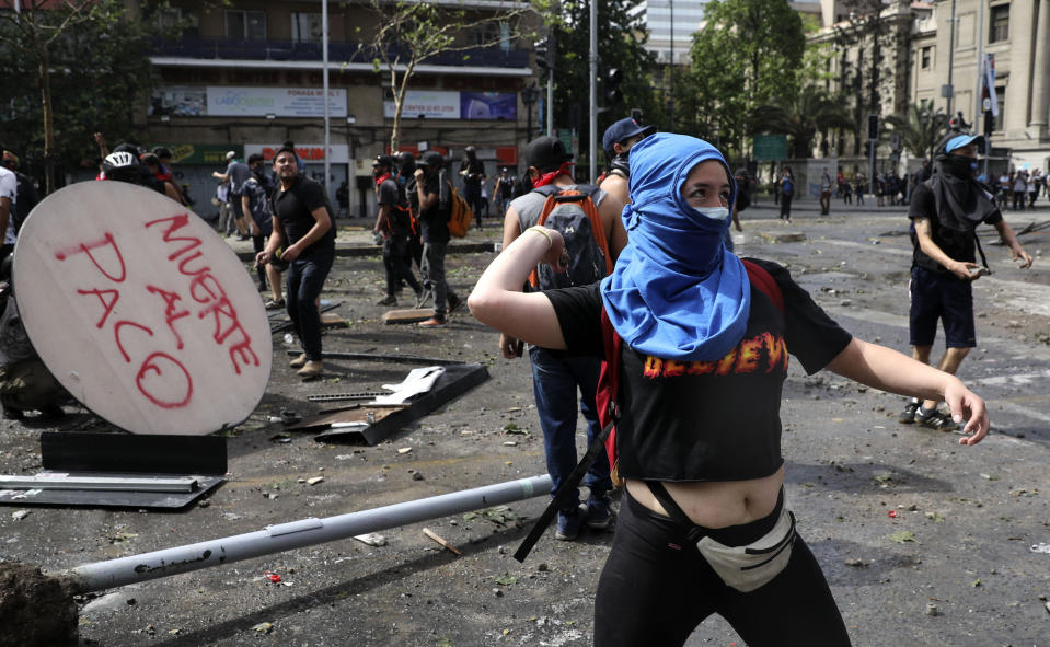 Protesters throw rocks at the police during a protest in Santiago, Chile, Wednesday, Oct. 23, 2019. Rioting, arson attacks and violent clashes wracked Chile as the government raised the death toll to 15 in an upheaval that has almost paralyzed the South American country long seen as the region's oasis of stability. (AP Photo/Rodrigo Abd)