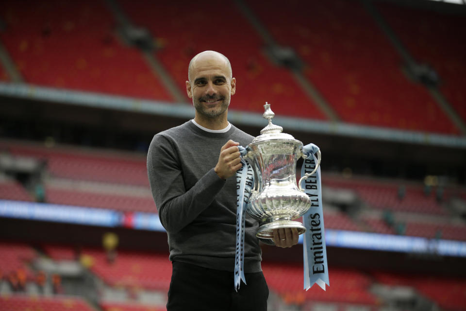 Manchester City's manager Pep Guardiola poses for a picture as lifts the trophy after winning the English FA Cup Final soccer match between Manchester City and Watford at Wembley stadium in London, Saturday, May 18, 2019. Manchester City won 6-0. (AP Photo/Tim Ireland)
