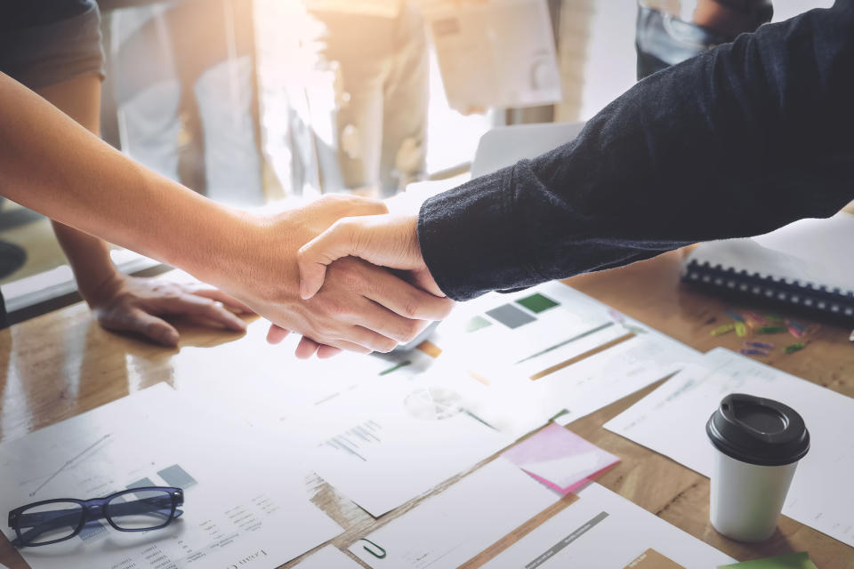 Two businesspeople shake hands over a conference table.