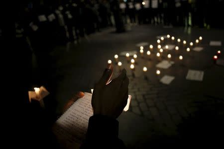 People hold candles and placards during a vigil to show solidarity with the victims of the Paris and Bamako attacks, in Madrid, Spain, November 22, 2015. REUTERS/Juan Medina