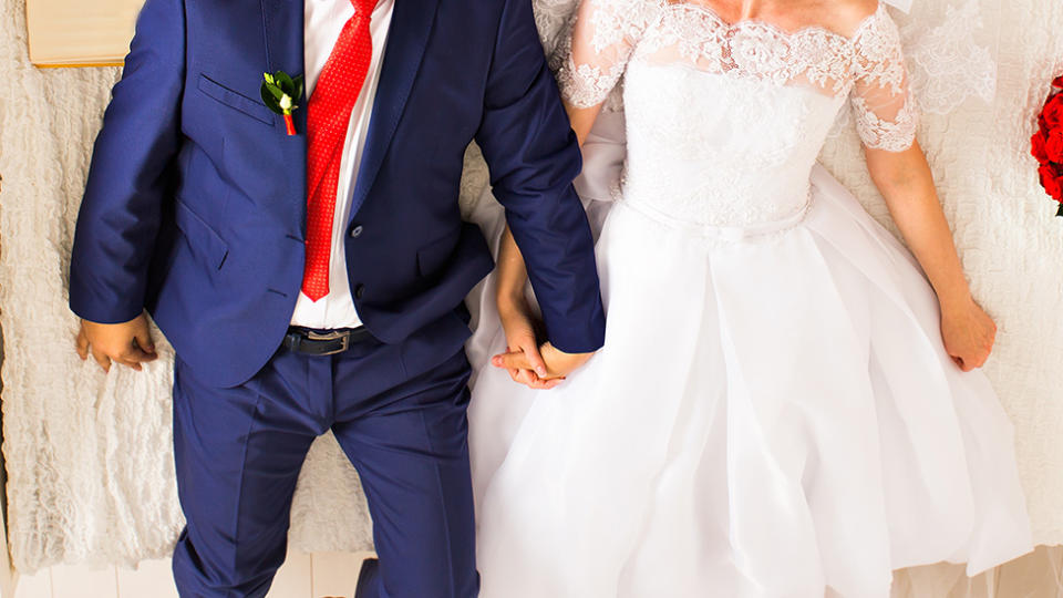 Bride and groom holding hands in bed together