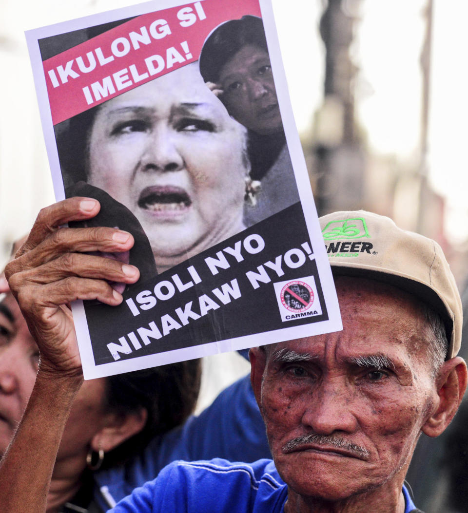 A protester displays a placard outside the anti-graft court Sandiganbayan as former Philippine First Lady Imelda Marcos was ordered to appear to explain her side for not attending last week's promulgation of the graft charges against her Friday, Nov. 16, 2018 in suburban Quezon city northeast of Manila, Philippines. A Philippine court found Imelda Marcos guilty of graft and ordered her arrest last week in a rare conviction among many corruption cases that she's likely to appeal to avoid jail and losing her seat in Congress. The placard reads: Return The Ill-gotten Wealth.! (AP Photo/Maria S. Tan)
