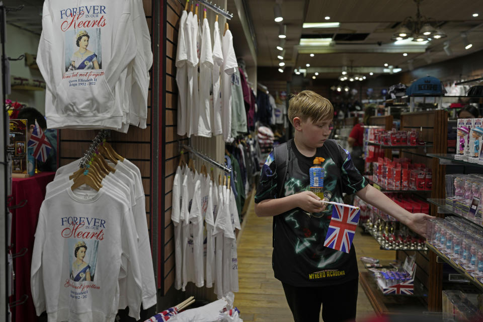 A boy looks at the toy figures of Queen Elizabeth II which are displayed for sale at a gift shop in London, Monday, Sept. 12, 2022. Just days after the death of Queen Elizabeth II, unofficial souvenirs have rolled out at royal-themed gift shops in London and online marketplaces like Amazon and Etsy. (AP Photo/Kin Cheung)