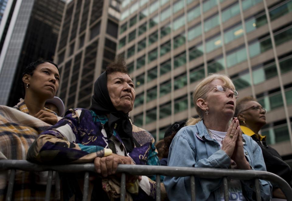 Women pray as they watch the Mass.