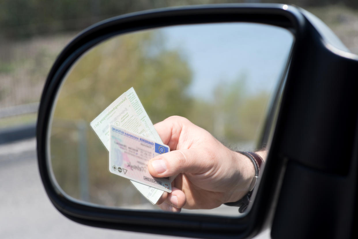 Ein Mann zeigt Führerschein und Fahrzeugschein bei einer Kontrolle