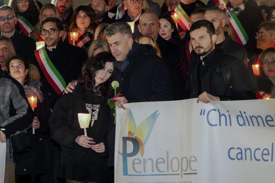 Gino Cecchettin, hugging his daughter Elena, attends a torchlit procession in Vigonovo, near Venice, northern Italy, Sunday, Nov. 19, 2023, after the police found the body of his other daughter Giulia, reportedly with multiple stab wounds and wrapped in plastic on Saturday in a ditch near Venice. Police in Germany over the weekend arrested Filippo Turetta, 21, who had been on the run since Nov. 11, when he was last seen arguing with Giulia Cecchettin. (Lucrezia Granzetti/LaPresse via AP)