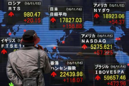 A man looks at an electronic board showing the stock market indices of various countries outside a brokerage in Tokyo, Japan, November 16, 2016. REUTERS/Toru Hanai