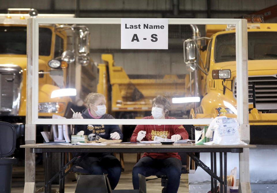 Sisters Kelly and Teal Rowe work behind a plexiglass barrier while waiting to verify voters at the town's highway garage facility, Tuesday, April 7, 2020, in Dunn, Wis. Voters in Wisconsin are casting ballots at polling places for the state's presidential primary election, ignoring a stay-at-home order over the coronavirus threat. (John Hart/Wisconsin State Journal via AP)