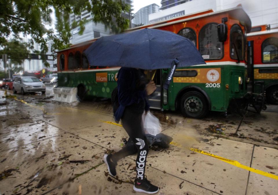 A person holds up an umbrella to guard against a light rain as cars and buses sit stalled due to flooding on Southwest First Avenue in the Brickell neighborhood of Miami, Saturday, June 4, 2022. (Daniel A. Varela/Miami Herald via AP)