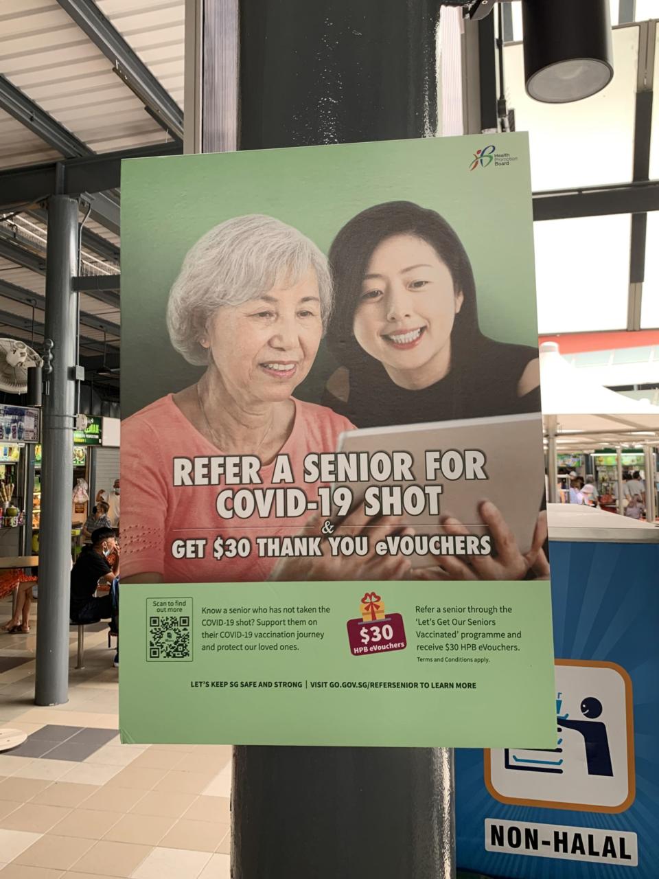 A poster promoting Covid-19 vaccinations at a hawker centre in Singapore.  (PHOTO: Bloomberg)