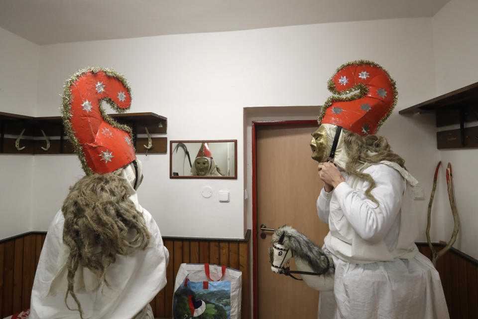 Revelers prepare for a traditional St Nicholas procession in the village of Valasska Polanka, Czech Republic, Saturday, Dec. 7, 2019. This pre-Christmas tradition has survived for centuries in a few villages in the eastern part of the country. The whole group parades through village for the weekend, going from door to door. St.Nicholas presents the kids with sweets. The devils wearing home made masks of sheep skin and the white creatures representing death with scythes frighten them. (AP Photo/Petr David Josek)