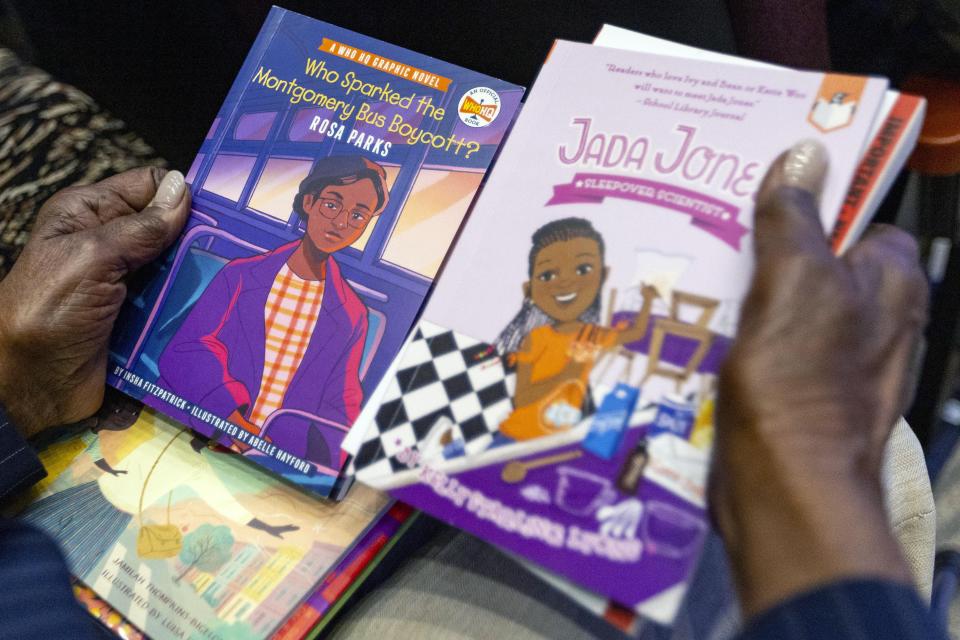 An attendee holds books that could potentially be banned by the state's newly adopted curriculum standards on African-American history during an education town hall regarding the state's newly adopted curriculum standards on African-American history at Antioch Missionary Baptist Church, Thursday, Aug. 10, 2023 in Miami Gardens, Fla. (D.A. Varela/Miami Herald via AP)