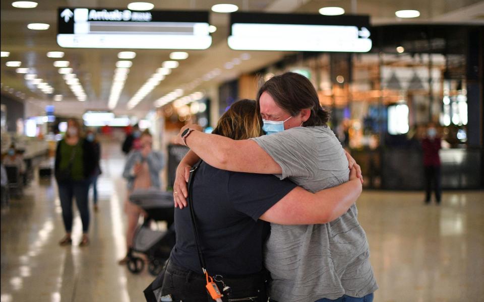 A mother (R) embraces her daughter upon her arrival from New Zealand at Sydney International Airport  - SAEED KHAN/AFP via Getty Images