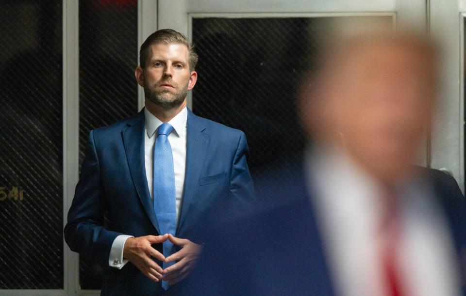 Eric Trump listens as his father, Donald Trump, speaks to the media in the courtroom hallway during the former president's criminal hush-money trial.