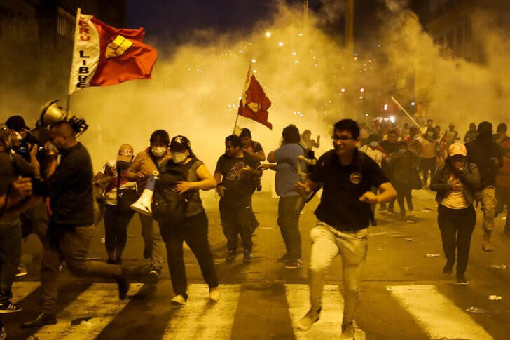 La gente huye de los gases lacrimógenos mientras los manifestantes participan en una protesta exigiendo la disolución del Congreso y la celebración de elecciones democráticas en lugar de reconocer a Dina Boluarte como presidenta de Perú, tras la destitución del líder peruano Pedro Castillo, en Lima