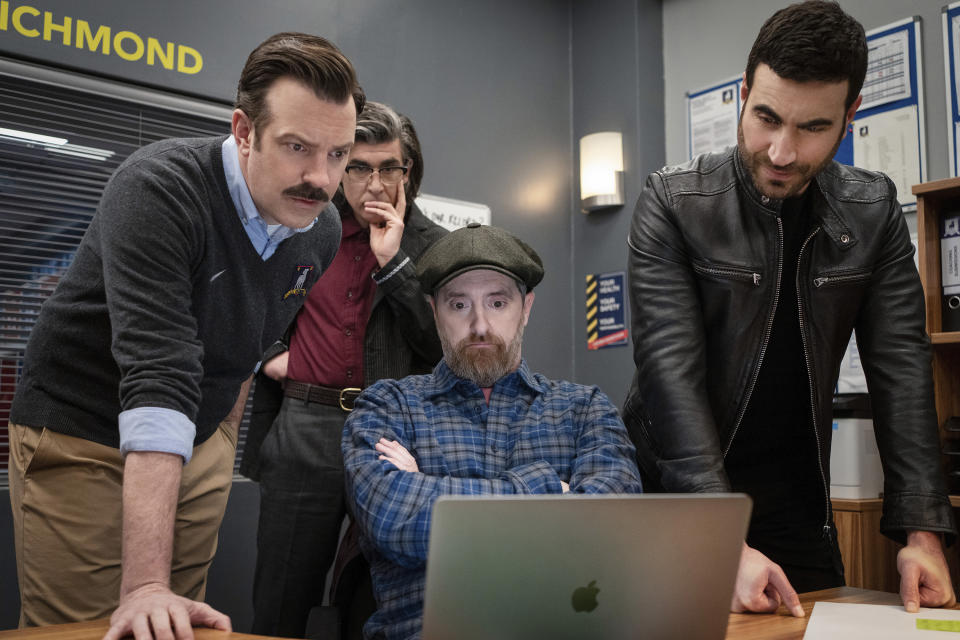 This image released by Apple TV+ shows Jason Sudeikis, from left, James Lance, Brendan Hunt and Brett Goldstein in a scene from "Ted Lasso." (Colin Hutton/Apple TV+ via AP)