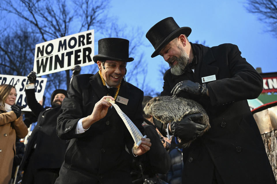Groundhog Club handler A.J. Dereume holds Punxsutawney Phil, the weather prognosticating groundhog, as vice president Dan McGinley reads the scroll during the 138th celebration of Groundhog Day on Gobbler's Knob in Punxsutawney, Pa., Friday, Feb. 2, 2024. Phil's handlers said that the groundhog has forecast an early spring. (AP Photo/Barry Reeger)