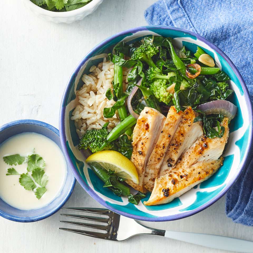 a blue bowl full of chicken and veggies and a smaller bowl full of dressing