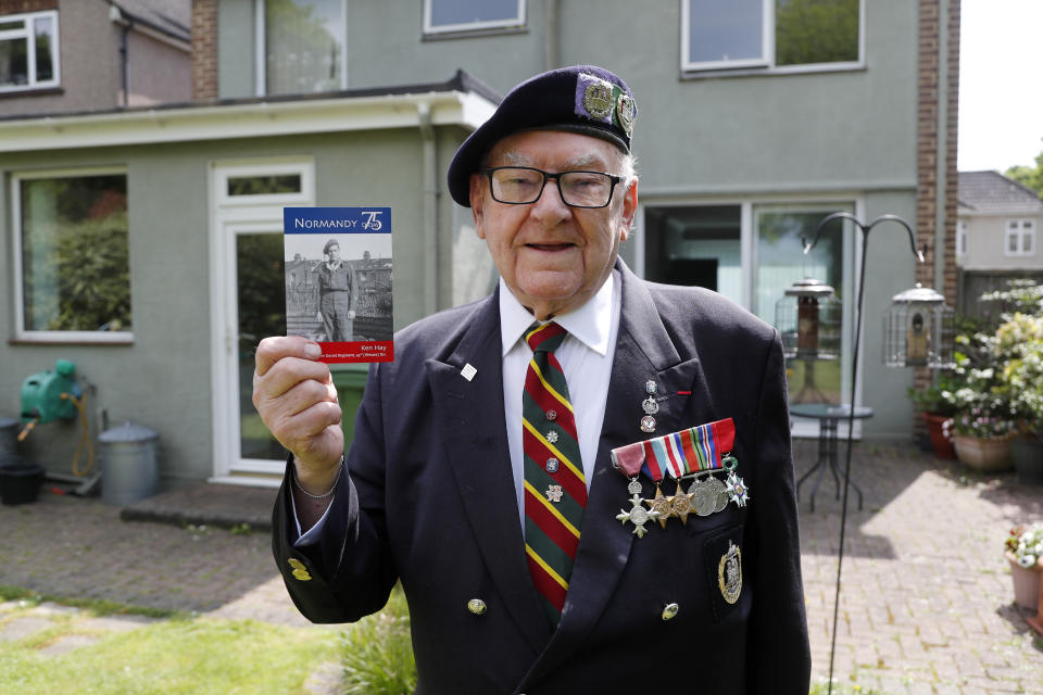 World War II veteran Ken Hay poses in front of his house with a picture of himself in uniform in London, Monday, May 4, 2020. VE-Day was the end of four days of celebration for Ken Hay. It began when the former prisoner of war got his first sight of home in almost a year from a Lancaster bomber he flew back in. (AP Photo/Frank Augstein)