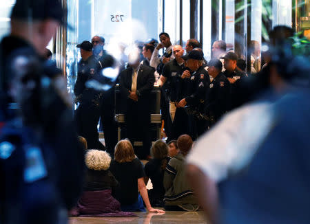 Protestors sit down in the lobby of Trump Tower as New York City Police officers (NYPD) prepare to make arrests in New York City, U.S., April 13, 2017. REUTERS/Brendan McDermid