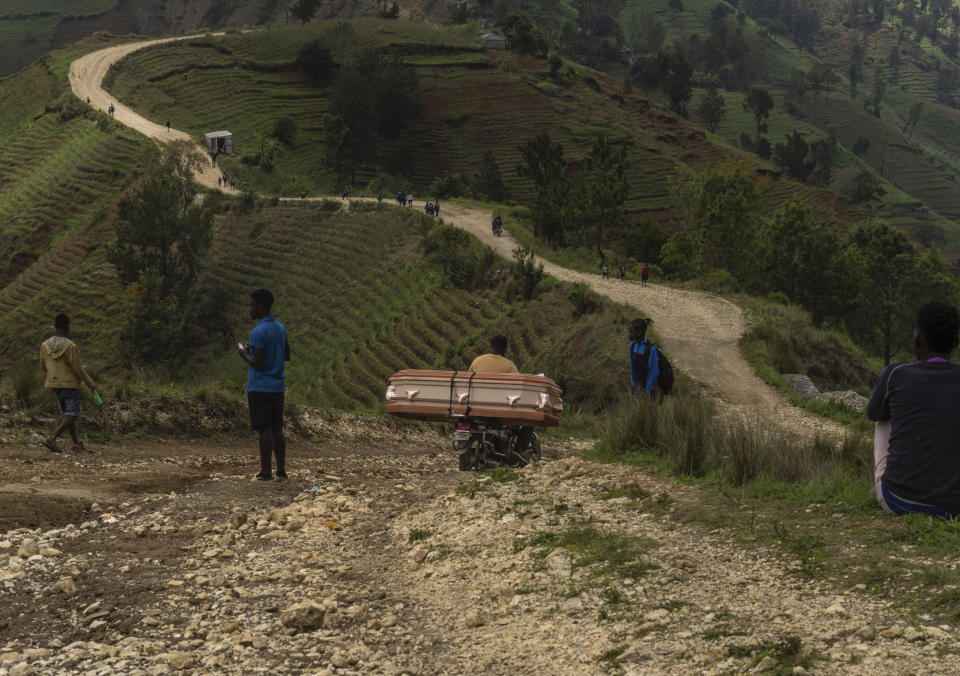 A motorcycle taxi navigates a rocky road, transporting a coffin for a family who live in the Kenscoff community, in the foothills of the Chaîne de la Selle mountain range, on the outskirts of Port-au-Prince, Haiti, May 14, 2024. (AP Photo/Ramon Espinosa)