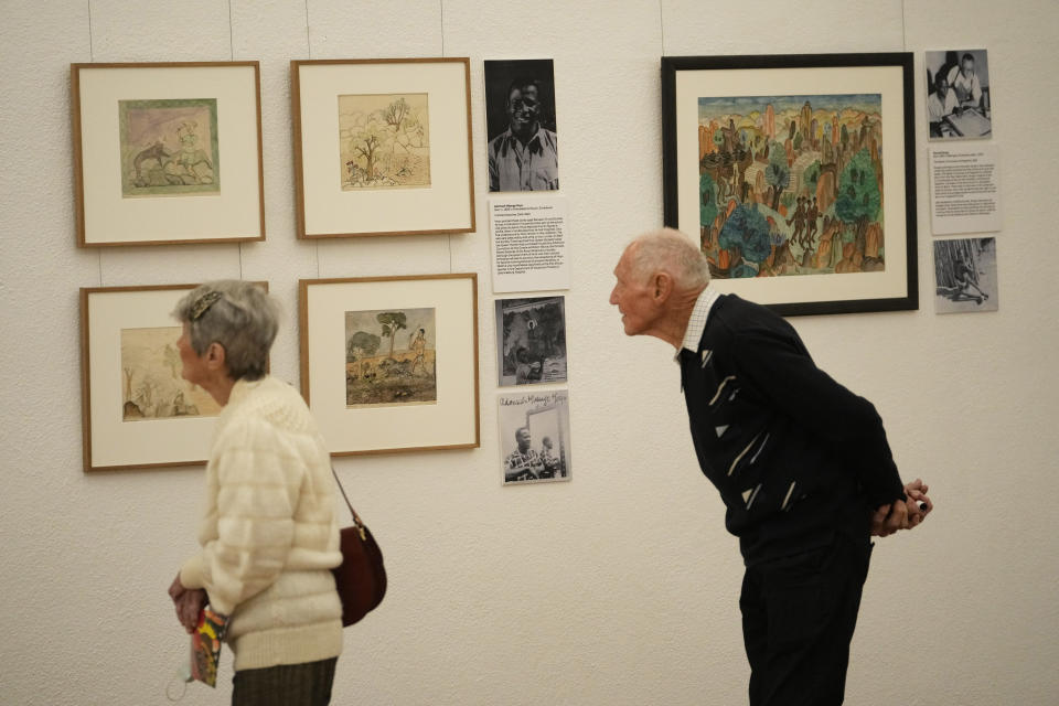 A couple takes a look at paintings done in the 1940s and 1950s by young Black students at Cyrene Mission School at the National Gallery of Zimbabwe, Friday July 22, 2022. The paintings are part of a historic exhibit, "The Stars are Bright," now showing in Zimbabwe for the first time since the collection left the country more than 70 years ago.(AP Photo/Tsvangirayi Mukwazhi)